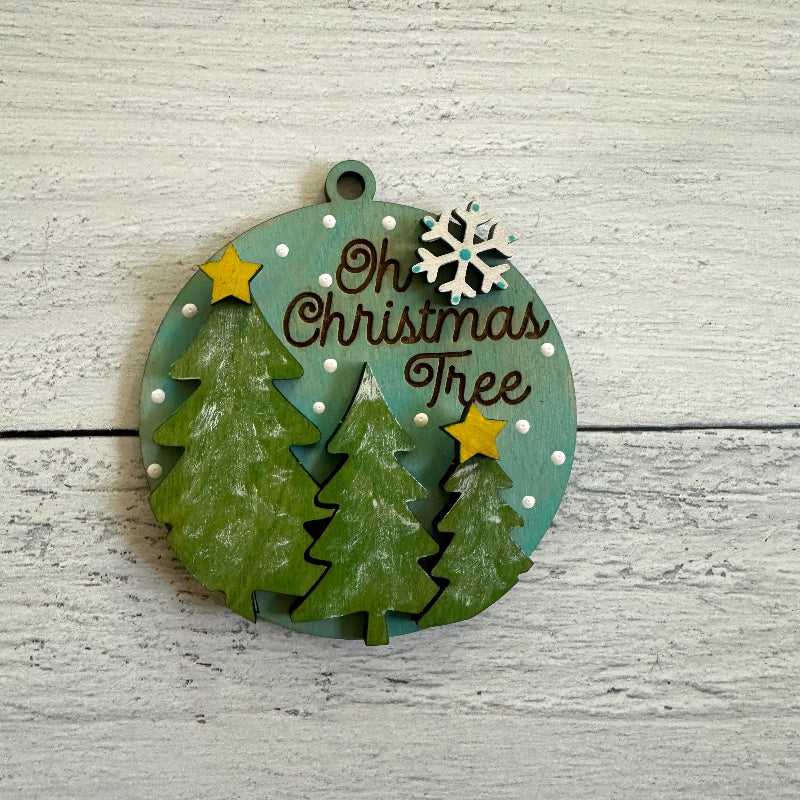 Decorative Christmas ornament with trees and text on a wooden surface