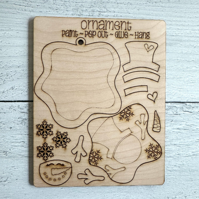 Wooden ornament craft kit with cut-out shapes and text on a light wooden surface